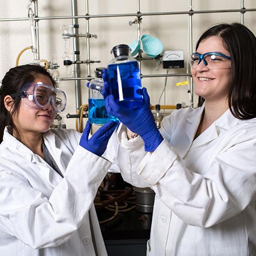 Two students inspecting beaker